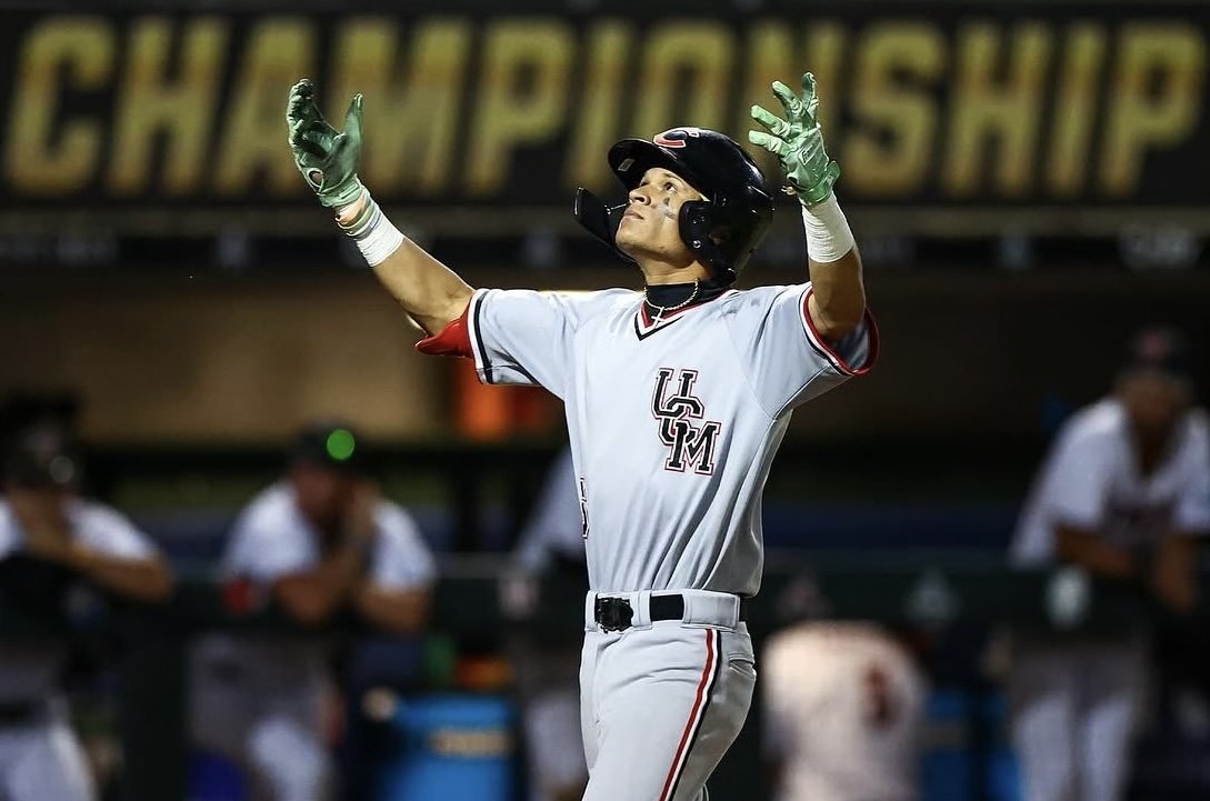 Mules player with his arms up in front of the championship banner